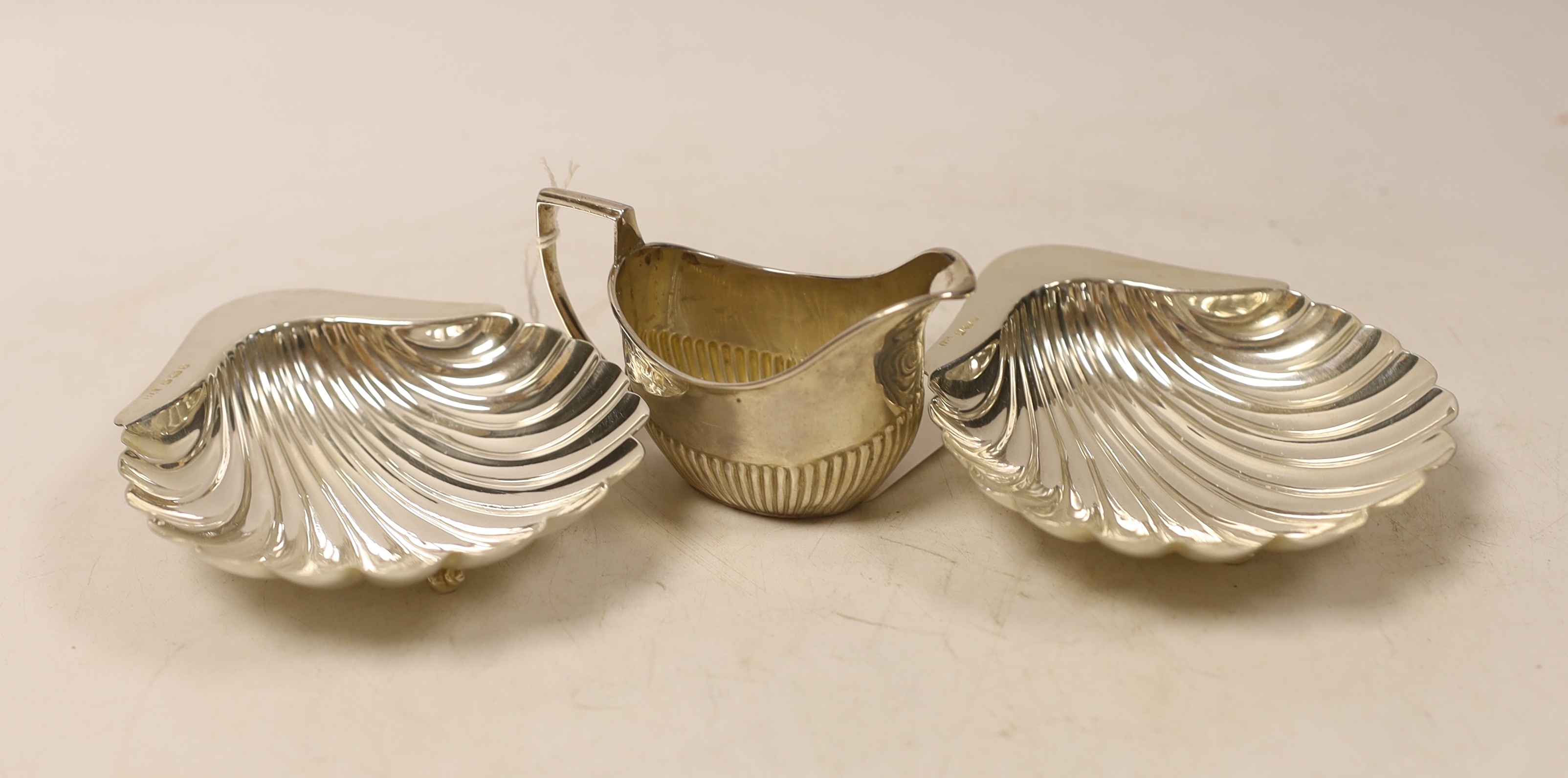 A pair of late Victorian silver scallop dishes, Atkin Brothers, Sheffield, 1890, 11.9cm and a small silver cream jug.